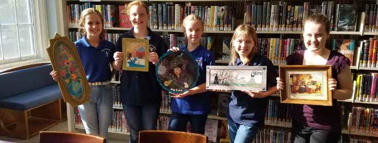 Five teenagers hold up paintings they modified during an Art Attack program
