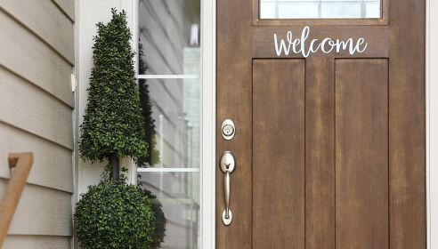 door that says welcome with decorative tree